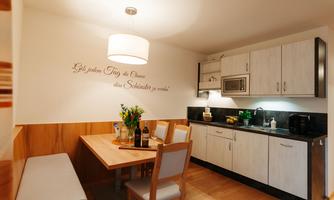 A modern kitchen with a dining table and chairs. An inspiring quote is on the wall.
