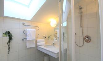 A modern bathroom with a shower and a sink. There are fresh towels and plenty of daylight through the skylight.