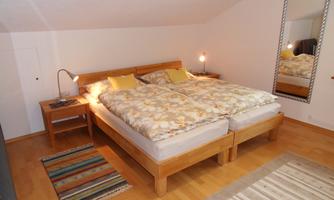 A cozy bedroom with a double bed and soft blankets. The room features beautiful lighting and a large mirror.