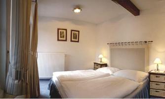 A cozy room with two single beds and soft colors.  
Windows with curtains and pictures on the wall add an inviting touch.
