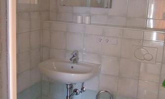 A clean bathroom with bright tiles. There is a sink, a toilet, and a mirror.