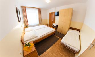 A cozy room with a double bed and a single bed. The room has light walls and is well-lit.