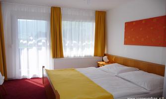 A cozy bedroom with a large bed and bright curtains. The warm colors create an inviting atmosphere.