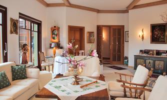 A bright living room with comfortable furniture and a decorative table. Flower arrangements and artistic details give the space an inviting atmosphere.