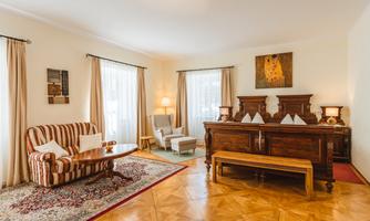 An inviting living room with a striped sofa and a wooden cupboard. Bright curtains and a rug add coziness to the space.