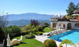 An elegant house with a pool, surrounded by green gardens and mountains in the background. The atmosphere is relaxed and inviting.