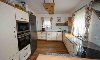 A modern kitchen with light cabinets and wooden surfaces. It is well equipped with appliances and has plenty of natural light.