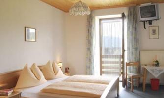 A cozy bedroom with a double bed and comfortable pillows. The room has a balcony with daylight and a calm atmosphere.