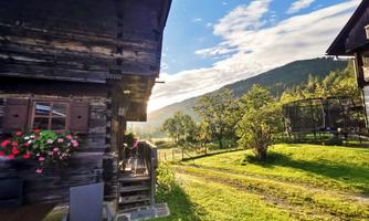 A picturesque mountain house amidst green meadows and gentle hills. The sun is shining, creating a cozy atmosphere.