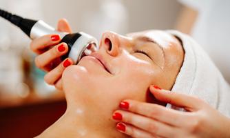 A woman is receiving a facial treatment with a modern device. Her skin is glowing as a professional works gently.