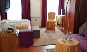 Double room with a bed, a table and a television. Large windows provide plenty of natural light.