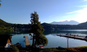 A tranquil lake surrounded by mountains and trees. A pier leads into the water, and the scenery is peaceful and inviting.