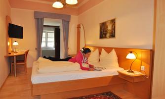 A cozy room with a double bed and a warm atmosphere. One person is relaxing on the bed and reading.