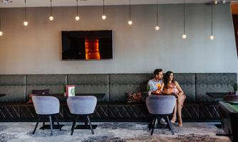 A modern café with elegant furnishings. A couple is sitting comfortably on a bench and enjoying drinks.