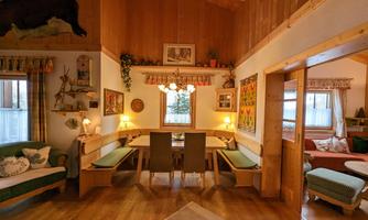 A cozy living space with a large dining table and benches. The wood paneling and decorative elements give the room a warm atmosphere.