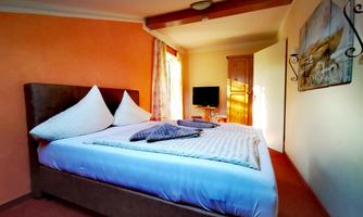 A cozy bedroom with a large bed and soft color nuances. The room features a television and plenty of daylight.