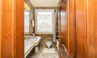 A modern bathroom with wood accents and a large mirror. The space is bright and cleanly designed, with a window view.