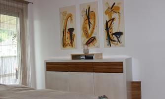 A modern room with a white dresser and colorful pictures on the wall. Daylight comes in through the window, creating a bright atmosphere.