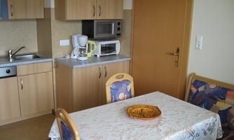 A small kitchen with a dining table and chairs. On the table is a decorative bowl.