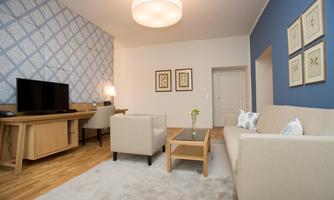 A modern living room with a television, a sofa, and a coffee table. The walls are in gentle colors, and there are decorative frames.