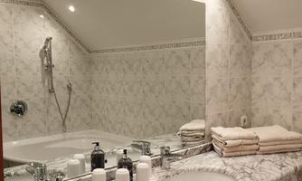An elegant bathroom with a marbled vanity and two sinks. White tiled walls and towels complement the stylish decor.