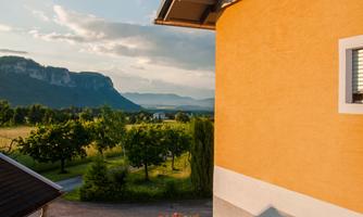 A beautiful house with an orange facade and a view of the mountains. The surroundings are green and peaceful, ideal for relaxing.