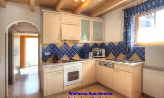 A bright kitchen with modern furniture and blue tiles. It includes kitchen appliances such as a stove, a microwave, and a refrigerator.