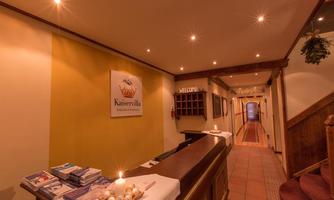 A reception area with a wooden desk and a cozy atmosphere.  
Walls in warm colors and an inviting path lead further inside.