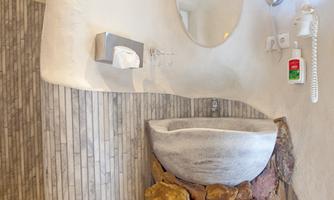 A modern bathroom with a stone sink and a large mirror. The walls are bright and elegantly designed, featuring a combination of smooth and textured surfaces.