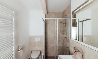 A modern bathroom with a shower, a sink, and a toilet. The walls are designed in warm beige and brown tones.