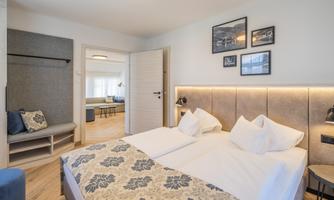 A modern bedroom with two single beds and elegant decor. The walls are light, and there are photos that complement the space.