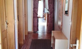 A bright hallway with wooden doors and a narrow carpet. At the end of the hallway, there is a living area with a cozy atmosphere.