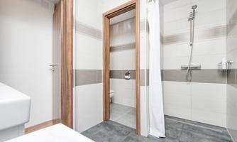 A modern bathroom with a shower and a sink. The walls are brightly tiled and there is a partition made of curtains.