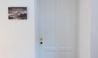 A white door with a golden doorknob. Next to the door hangs a sign with the inscription "SUN VIEW" and a picture of mountains.