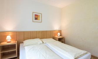 A cozy bedroom with a double bed and soft light from bedside lamps. The walls are light, and the room feels inviting and calm.