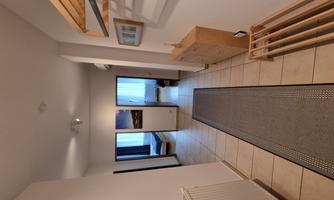 A bright hallway with a long runner and two open doors to adjacent rooms. On the wall, wooden shelves and a picture frame are hanging.