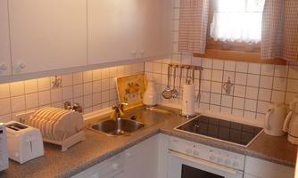 A bright kitchen with modern appliances and a cozy atmosphere. The room includes a sink, a stove, and some kitchen utensils.