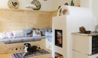A cozy living room with a wooden bench and a fireplace. A dog is lying relaxed on a carpet.