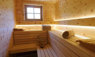 A cozy wooden sauna with a wooden bench and towels. Soft light creates a relaxing atmosphere.