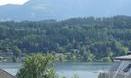 A serene landscape with a lake and gentle hills in the background. The sky is clear and nature is lush green.