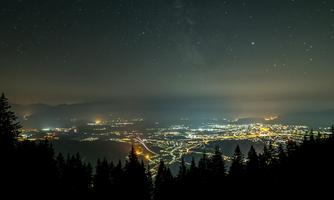 A beautiful view of the city at night, illuminated by many lights. The sky is clear and full of stars.