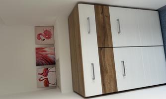 A modern cabinet with a wooden surface and white drawers. Above it are pictures of flamingos in soft colors.