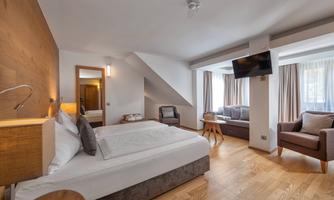 A modern bedroom with a large bed and a cozy seating area.  
Large windows let in plenty of light and create an inviting atmosphere.