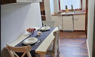 A cozy kitchen with a small dining area. The table is set with dishes and light falls through a window.