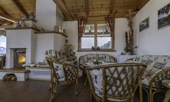 A cozy living space with rattan chairs and a cool fireplace. Large windows offer a lovely view of the landscape.