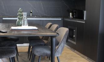 Modern kitchen with a dining table and elegant chairs. The decor is stylish and functional, featuring a minimalist aesthetic.