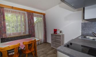 A cozy kitchen with a dining table and chairs. Bright windows let in a lot of daylight.