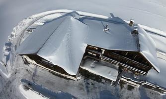 A beautiful, large house, surrounded by deep snow. The roof ridge is covered with snow, and the surroundings appear calm and wintry.