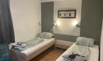 A simple room with two single beds and modern design. The walls are painted in gentle colors and there is a small dresser between the beds.