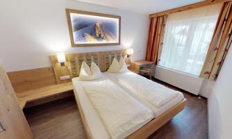 A modern hotel room with two beds and wood interior. A large window lets in plenty of light and creates a pleasant atmosphere.